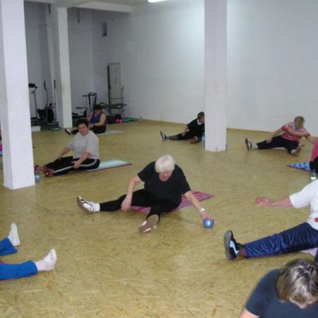 Członkowie kulbu wykonują ćwiczenia fizyczne na podłodze